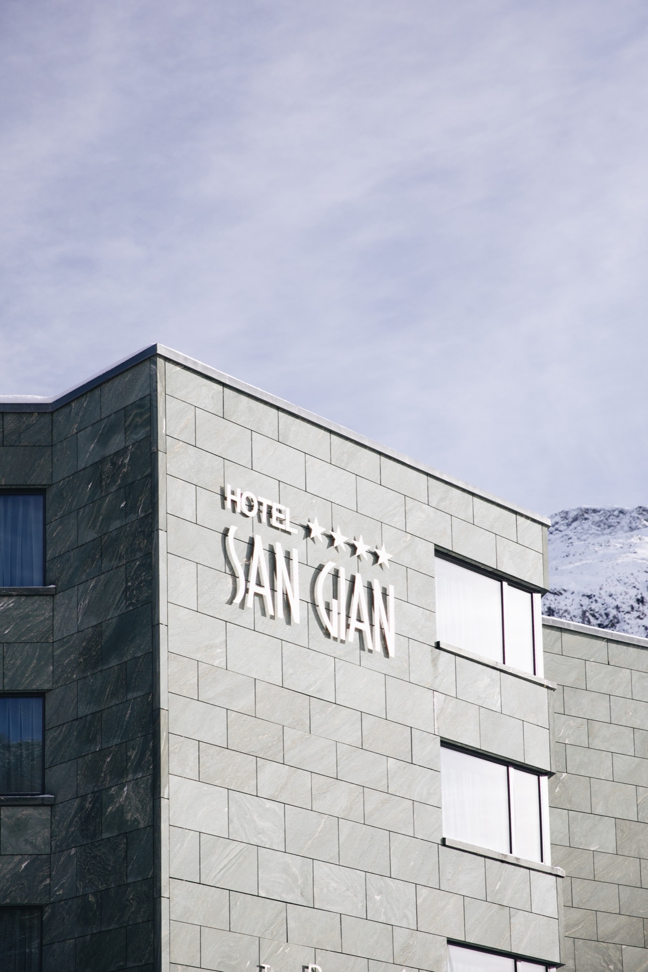 The façade of a partner hotel against the mountains.